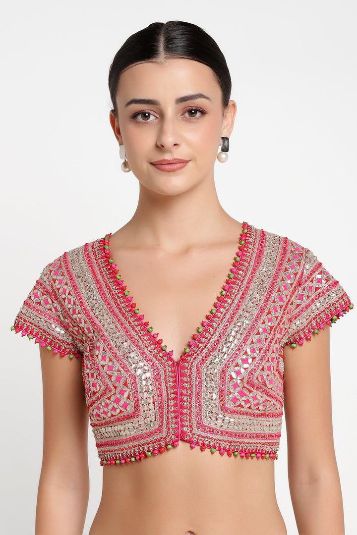 Woman wearing a pink and silver embroidered blouse with tassels on a white background