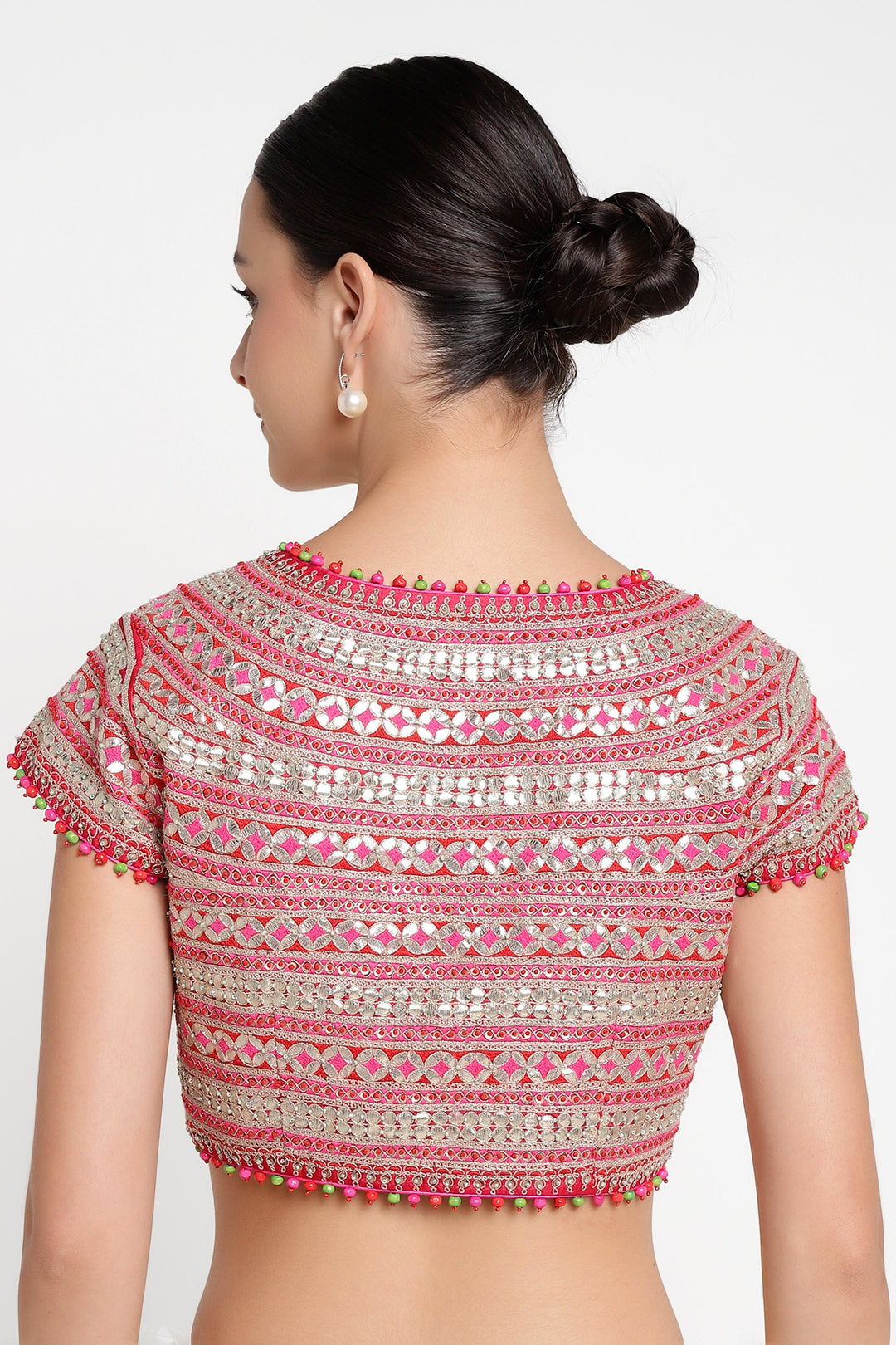 Woman wearing a pink and silver embroidered blouse on a white background