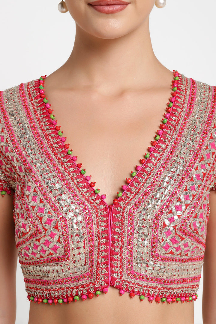 Close-up of a embroidered blouse with pink and green details on a neutral background