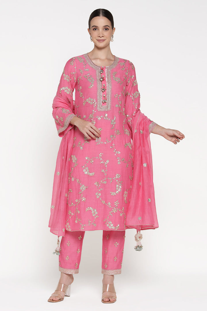 Woman wearing a pink traditional outfit with floral patterns on a white background