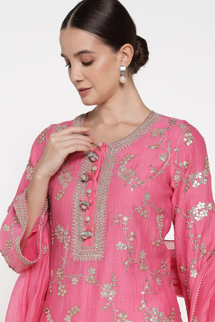 Woman wearing a pink embroidered traditional outfit on a white background