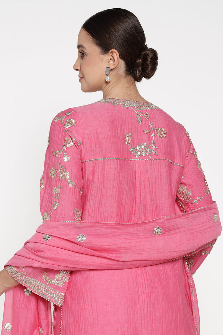 Woman wearing a pink traditional outfit with silver embroidery on a white background