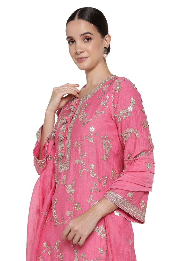 Woman wearing a pink traditional outfit with intricate embroidery on a white background