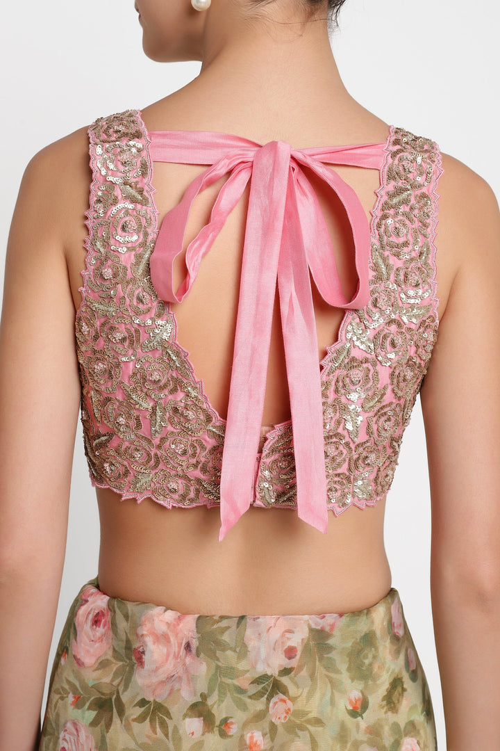Back view of a pink embroidered top with a bow and floral skirt on a white background