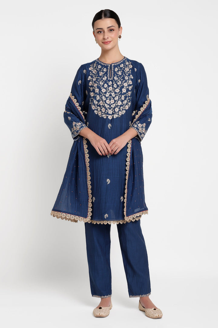 Woman wearing a blue embroidered traditional outfit on a white background