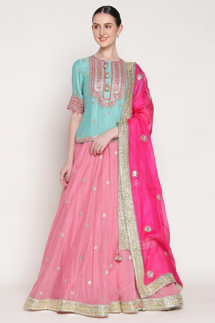 Woman wearing a traditional outfit with a pink and blue color scheme on a white background