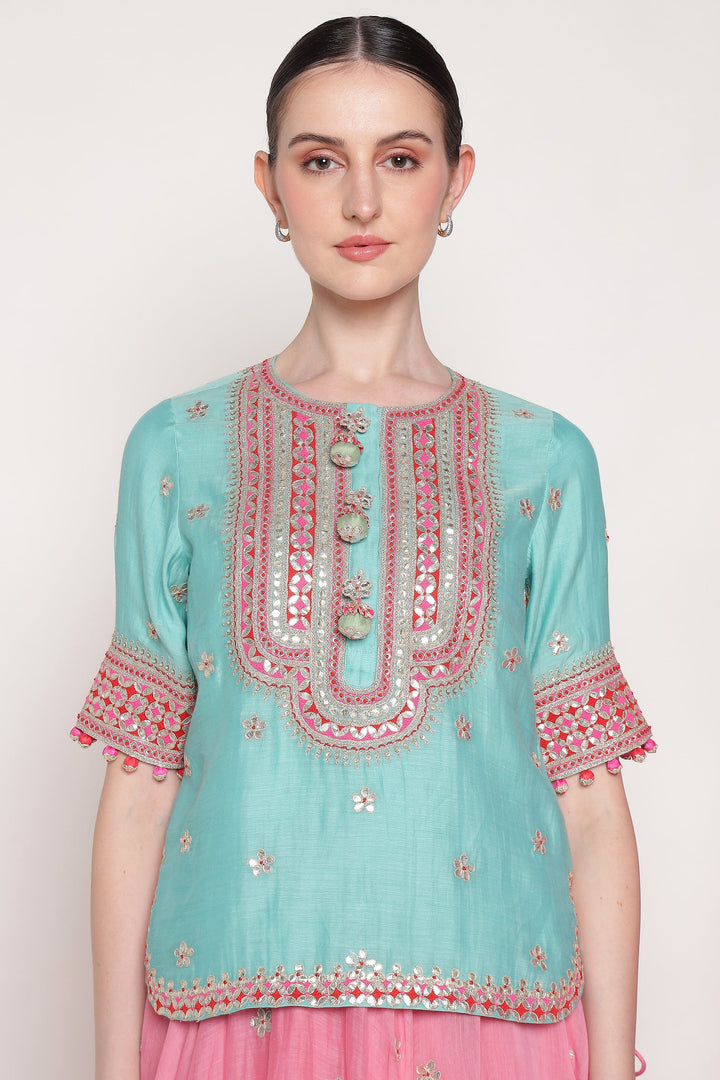 Light blue embroidered top with pink details on a white background