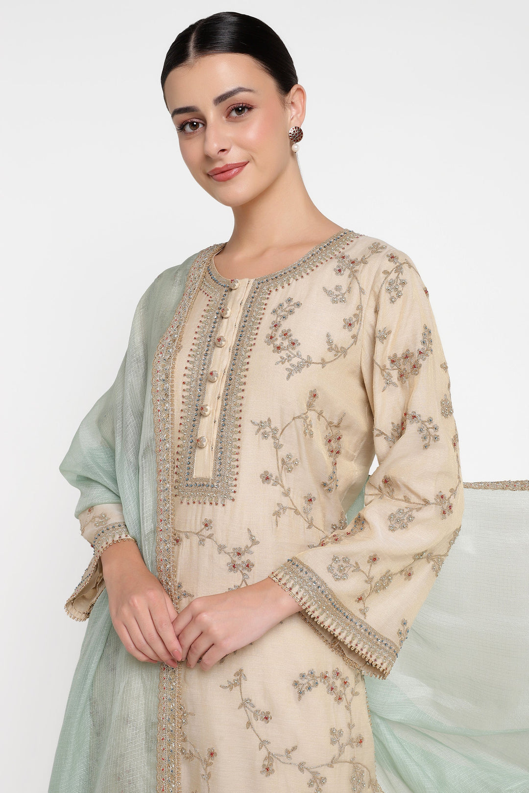 Woman wearing a beige embroidered outfit with a light green dupatta on a white background