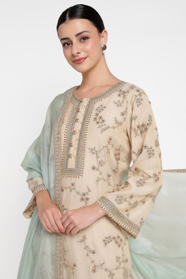 Woman wearing a beige embroidered outfit with a light green dupatta on a white background