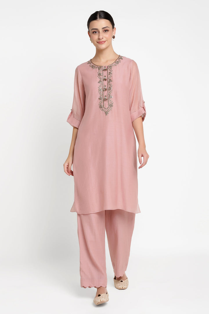 Woman wearing a pink kurta with embroidery on a white background