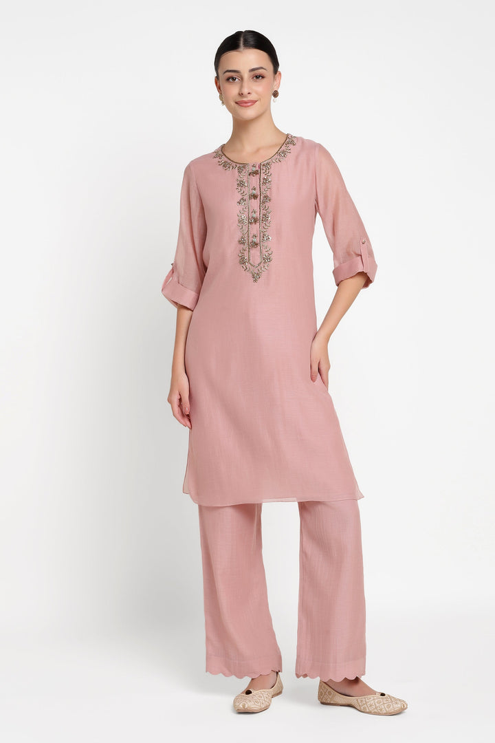Woman wearing a pink kurta with embroidery on a white background
