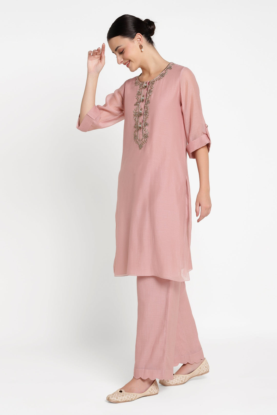 Woman wearing a pink outfit with embroidery on a white background