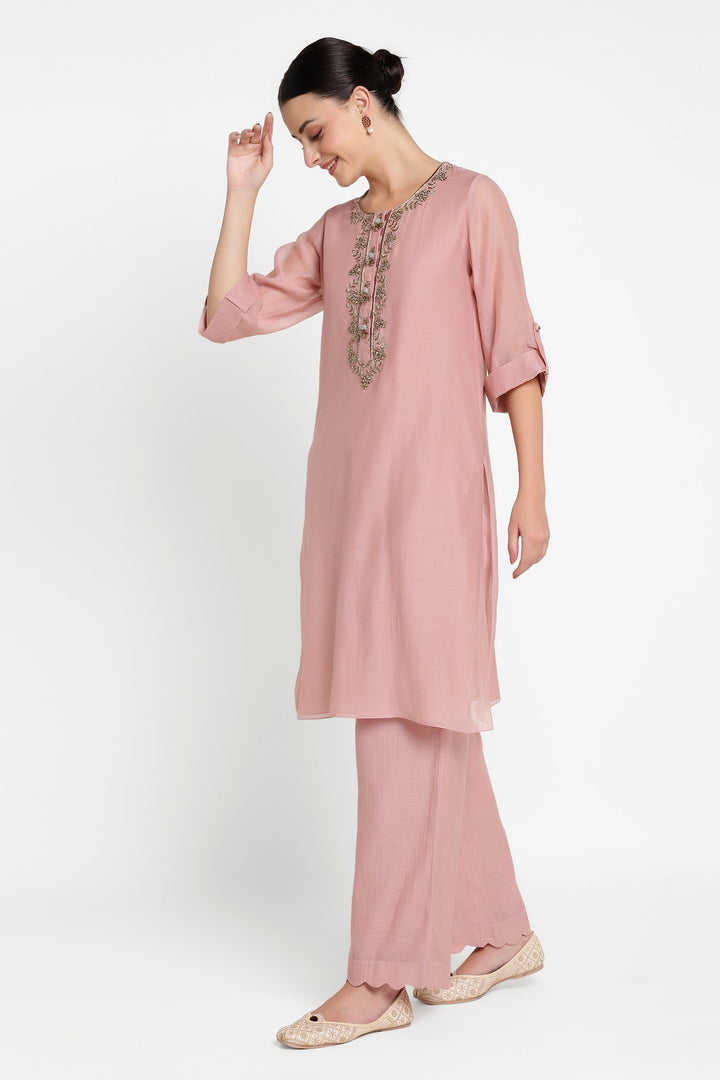 Woman wearing a pink outfit with embroidery on a white background