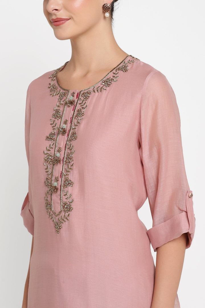 Pink dress with intricate embroidery on a white background
