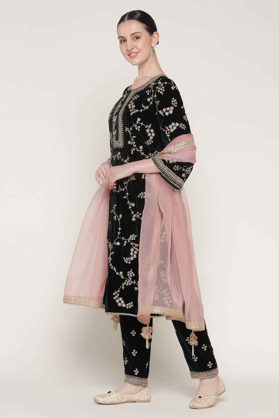 Woman wearing a black embroidered outfit with pink dupatta on a white background