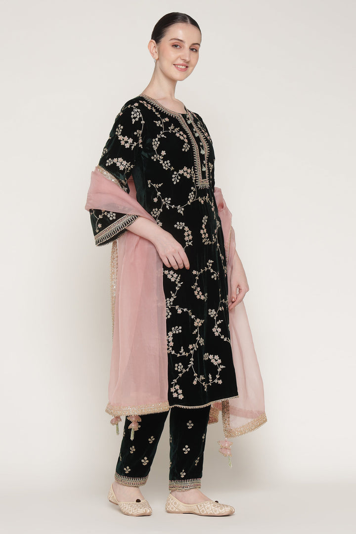 Woman wearing a black embroidered outfit with a pink dupatta on a white background