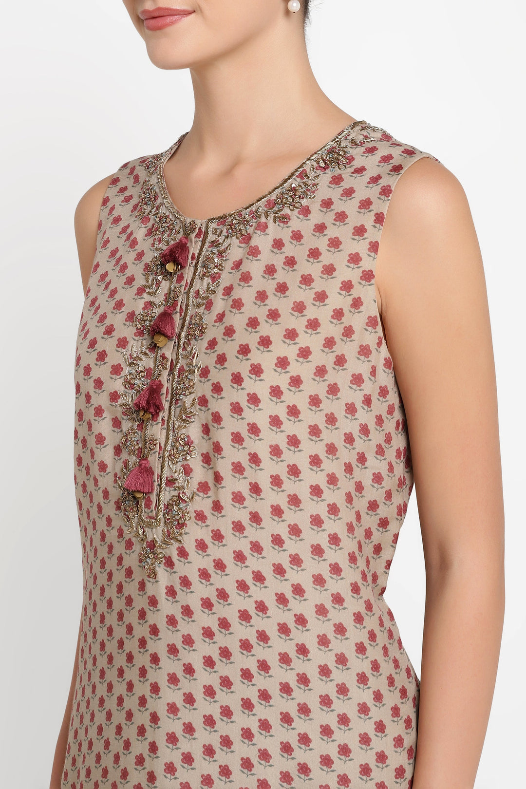 Woman wearing a sleeveless top with floral pattern and embroidered details on a white background