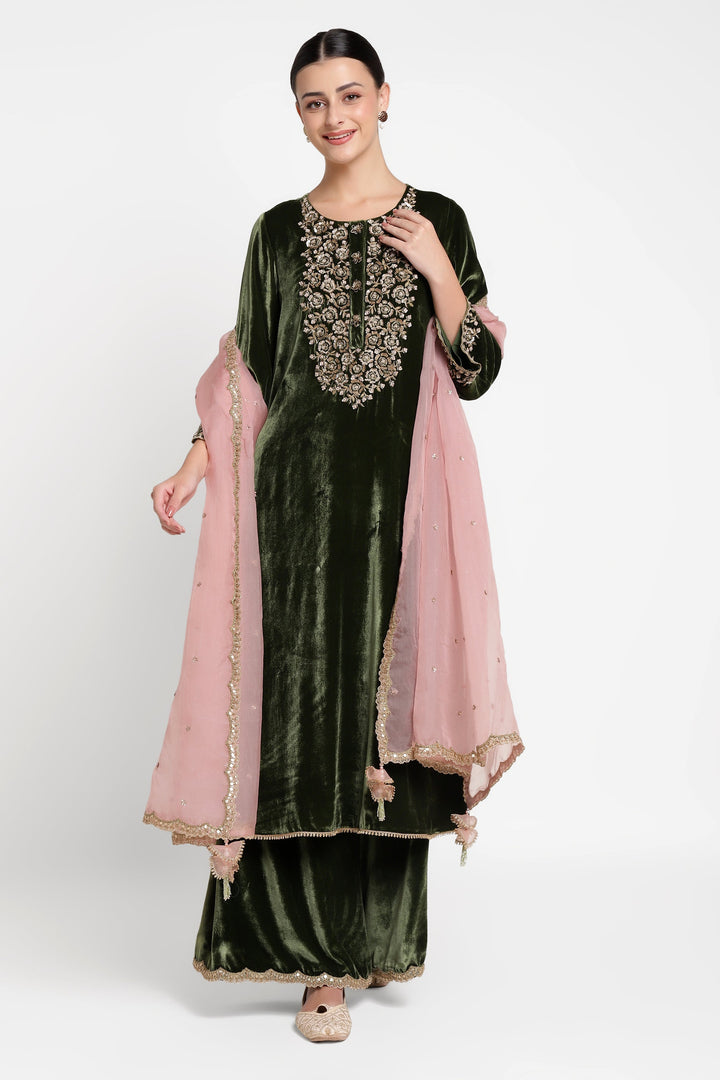Woman wearing a green velvet outfit with pink dupatta on a white background