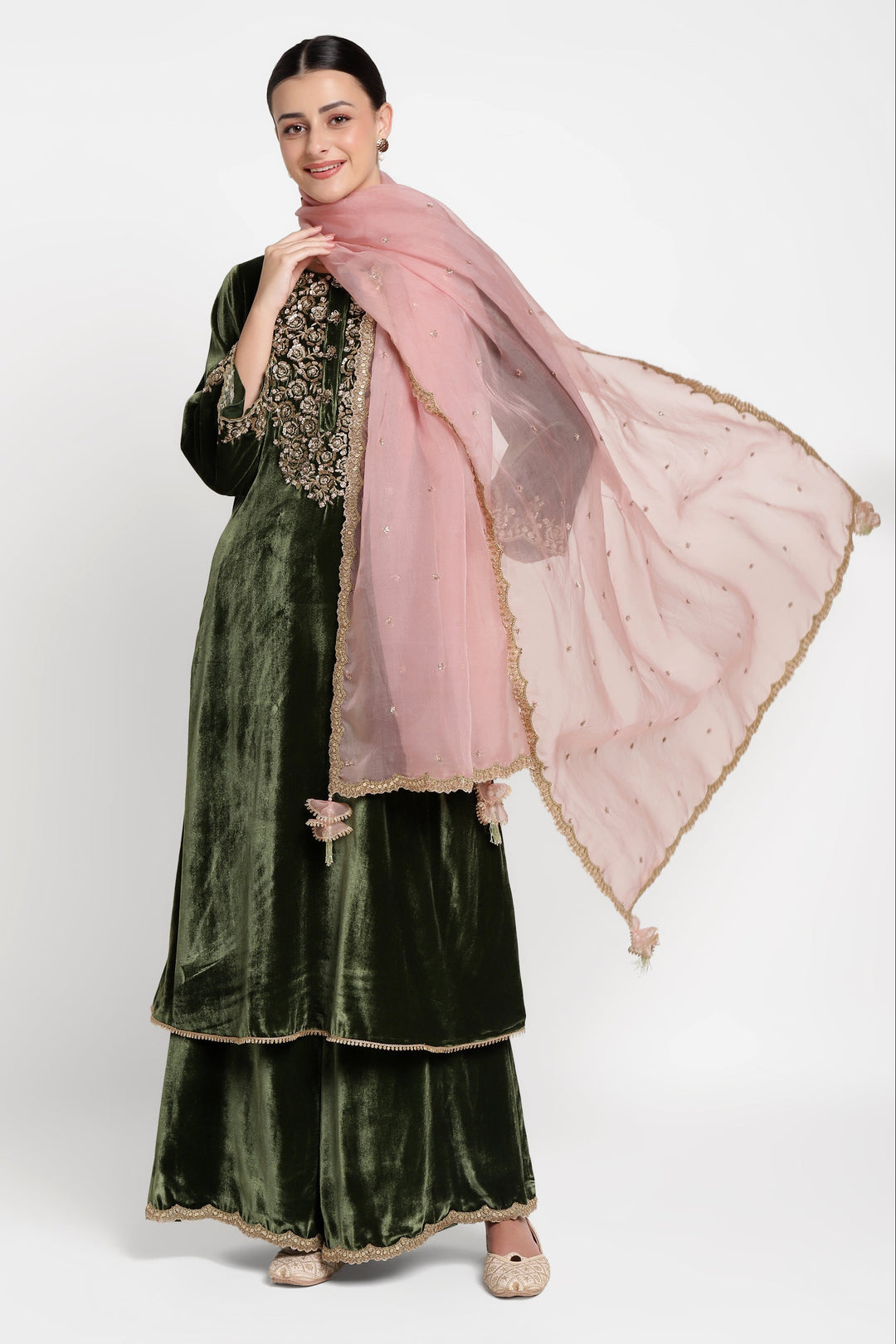 Woman wearing a green traditional outfit with a pink dupatta on a white background