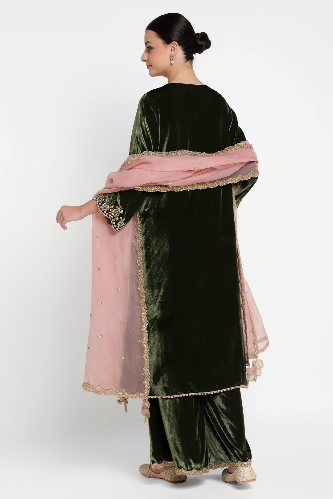 Woman wearing a green velvet outfit with a pink dupatta on a white background