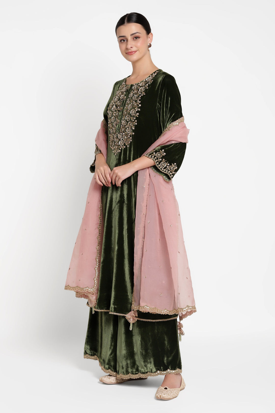 Woman wearing a black and green embroidered outfit with a pink dupatta on a white background