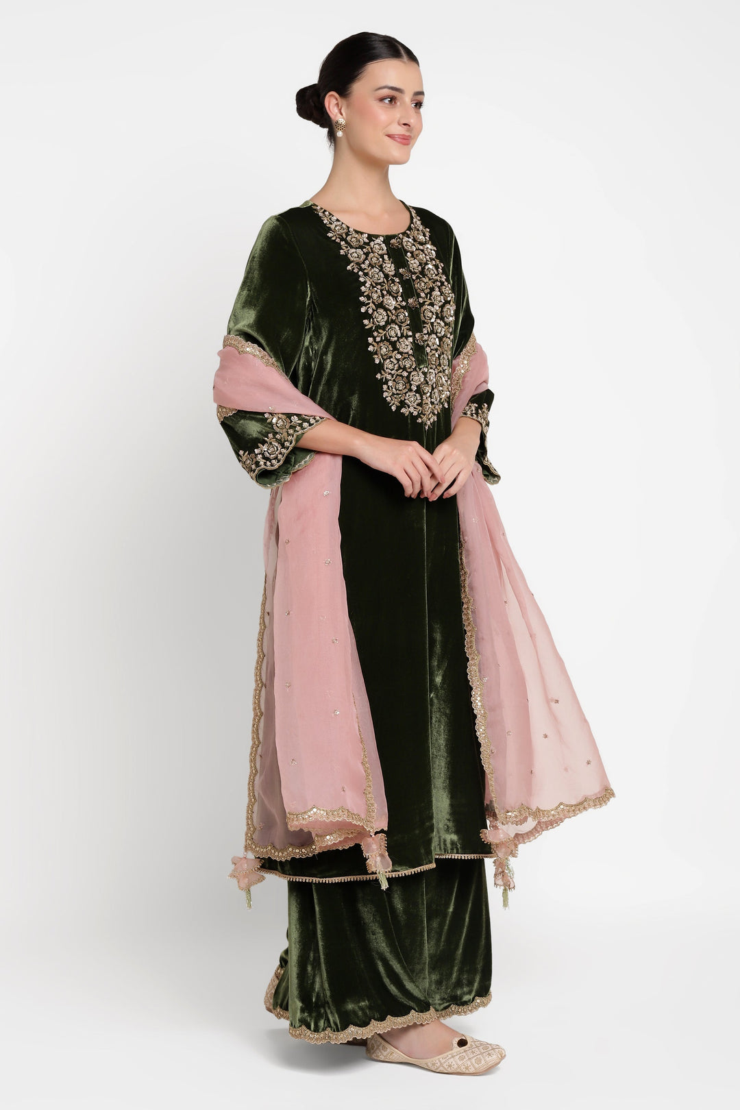 Woman wearing a green and pink traditional outfit with floral embroidery on a white background