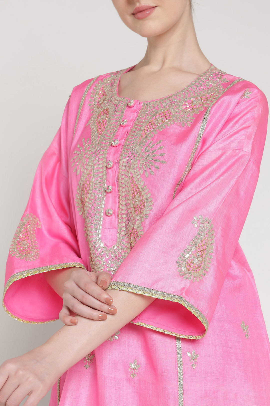 Pink embroidered traditional outfit on a plain background