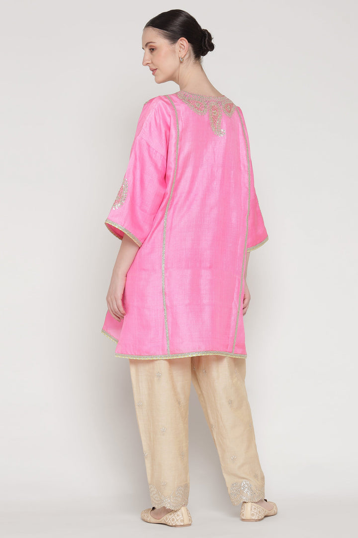Woman wearing a pink kurta with beige pants on a white background