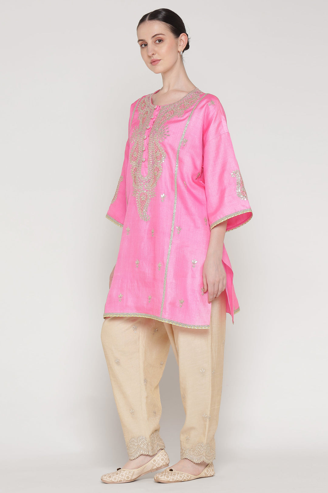 Woman wearing a pink kurta with beige pants on a white background