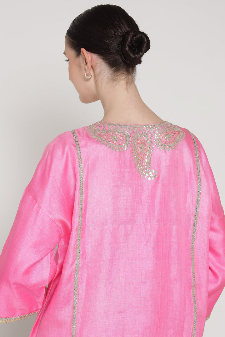 Pink traditional outfit with intricate detailing on a plain background
