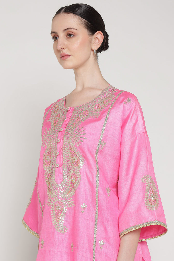 Pink embroidered garment worn by a model on a white background