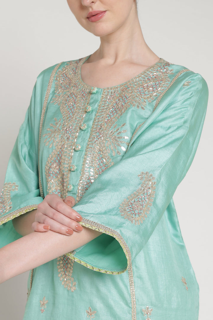 Light blue traditional outfit with intricate gold embroidery on a plain background