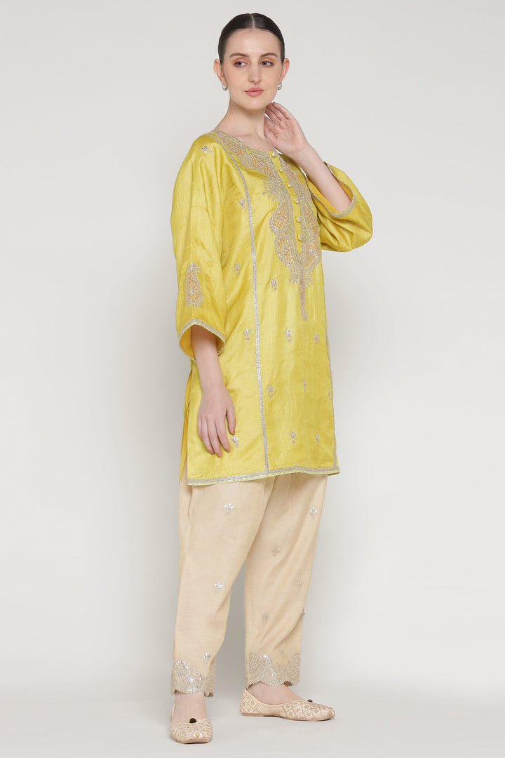Woman wearing a yellow kurta with beige pants on a white background