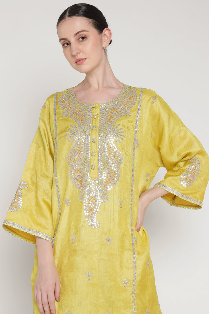 Woman wearing a yellow embroidered kurta against a white background