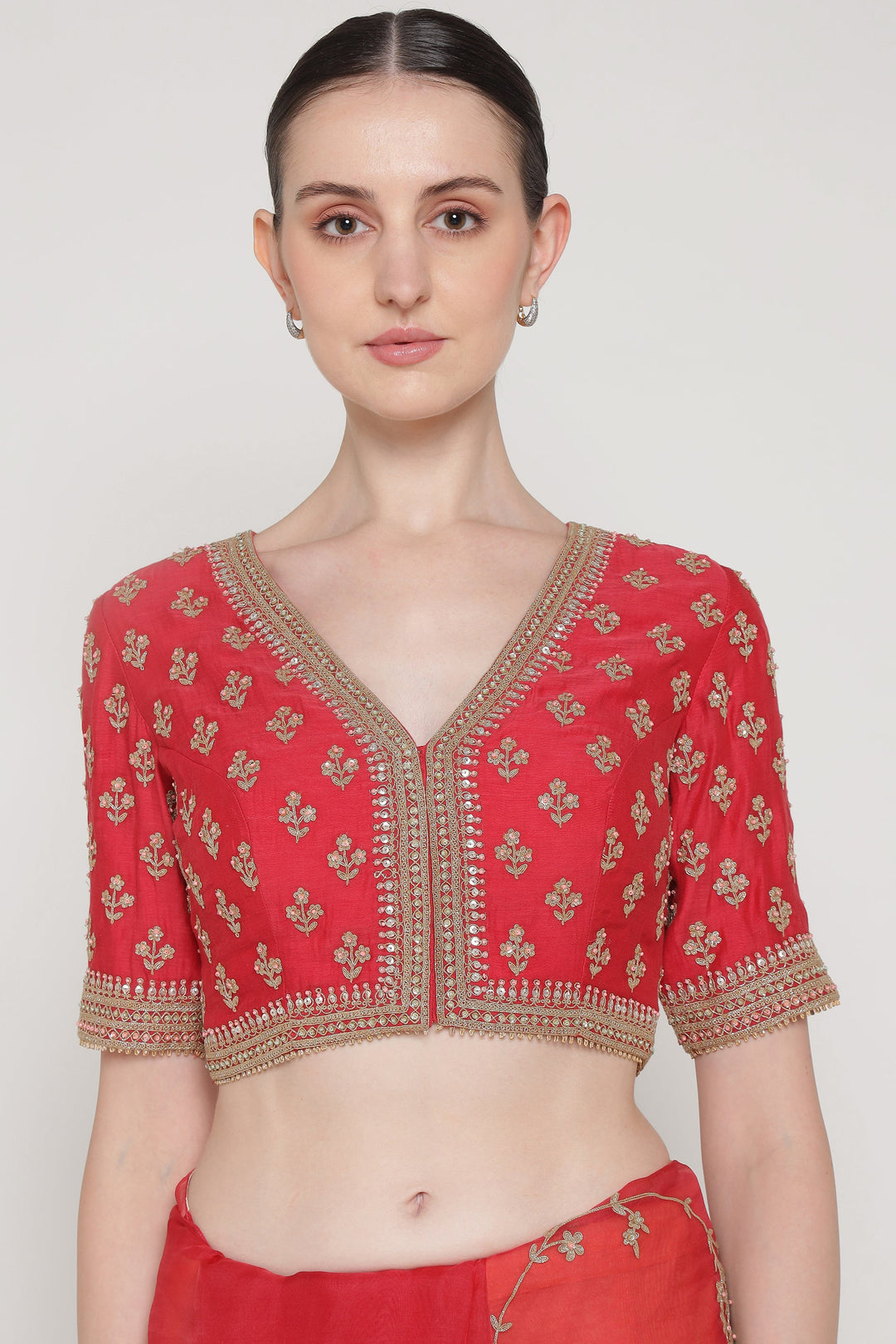 Red embroidered blouse worn by a model on a white background