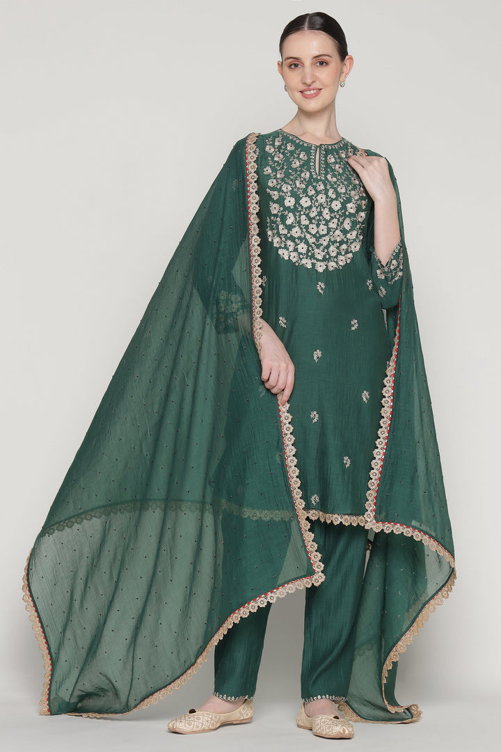 Woman wearing a green traditional outfit with intricate embroidery on a white background