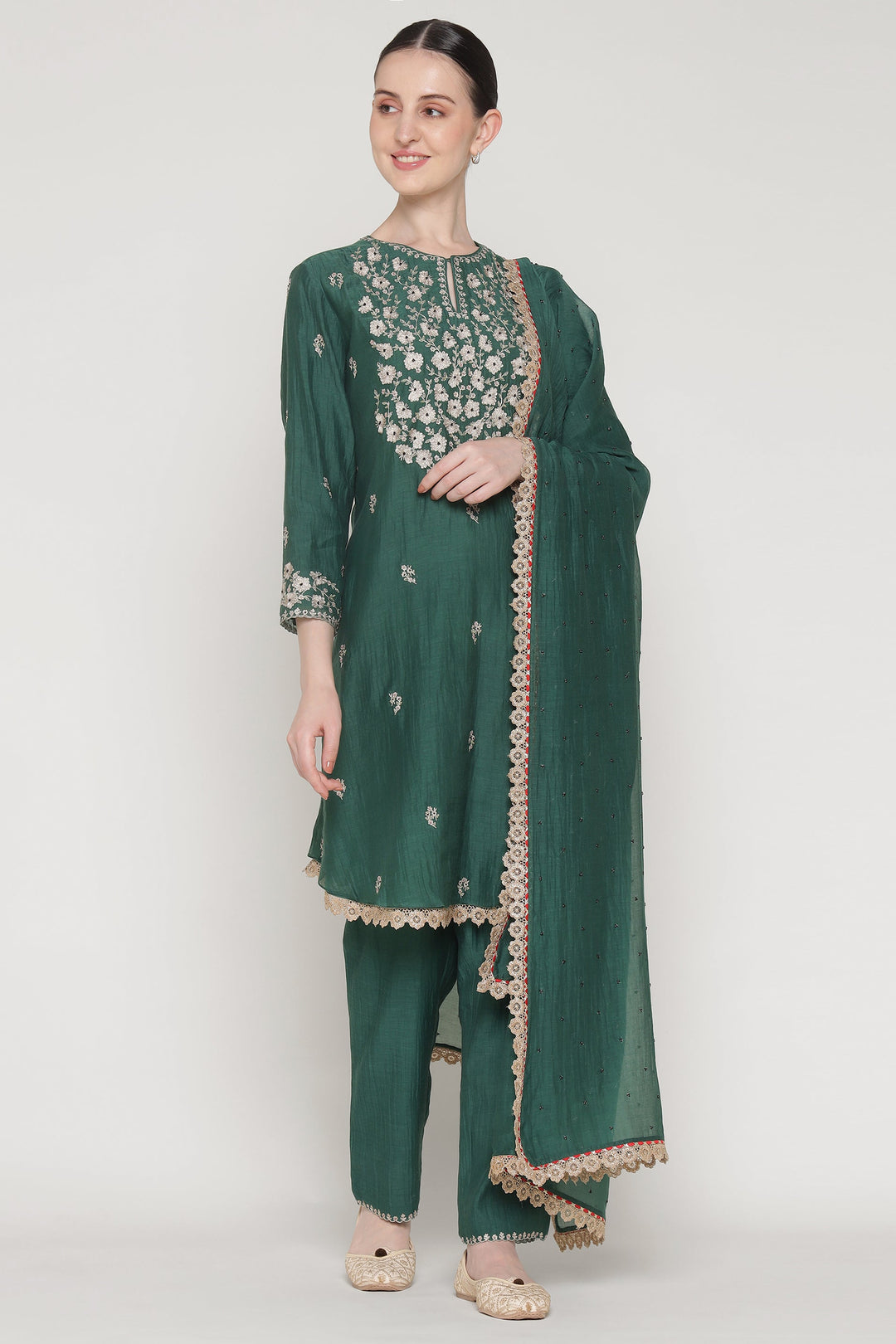 Woman wearing a green traditional outfit with floral embroidery on a white background