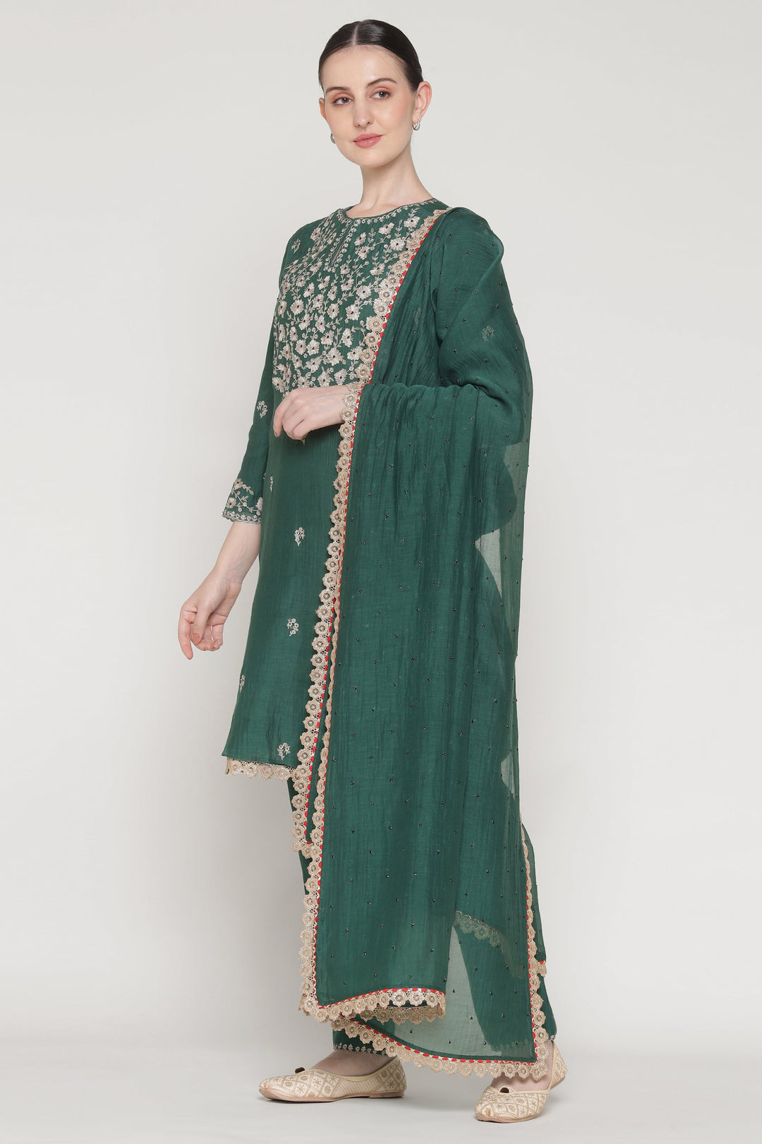 Woman wearing a green traditional outfit with floral patterns on a white background