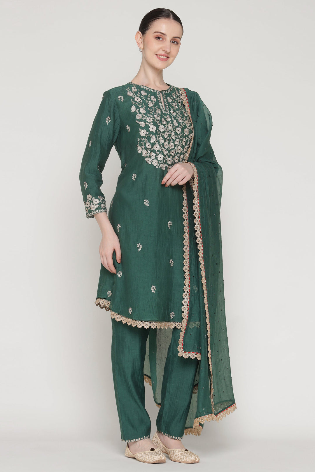 Woman wearing a green embroidered traditional outfit on a white background