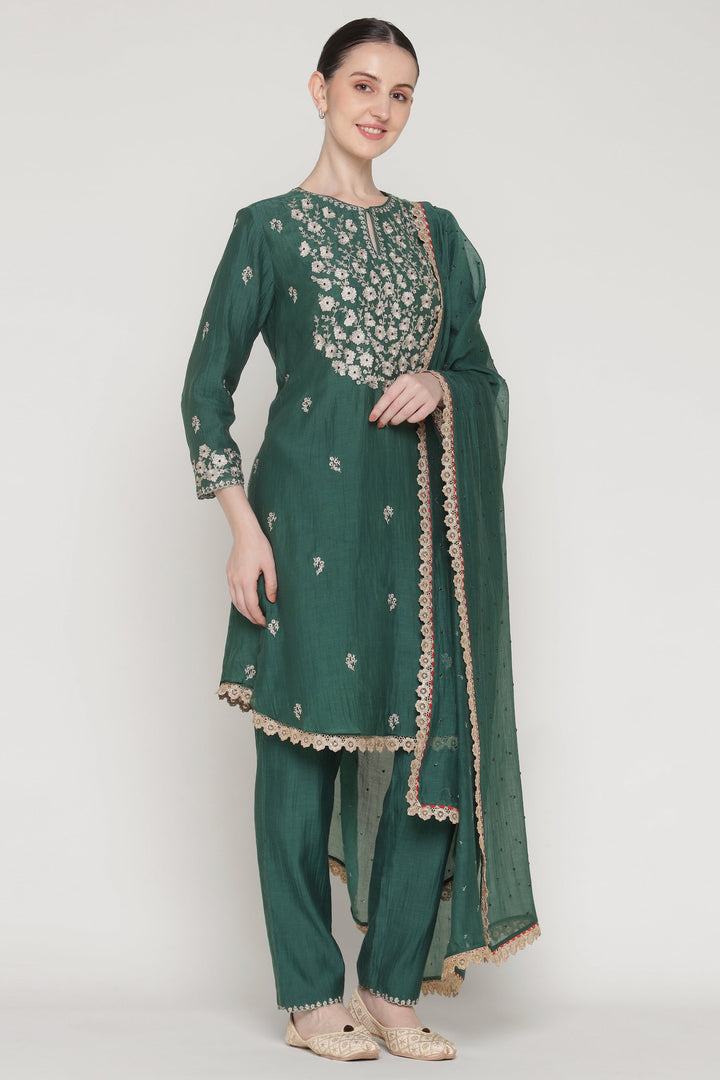 Woman wearing a green embroidered traditional outfit on a white background