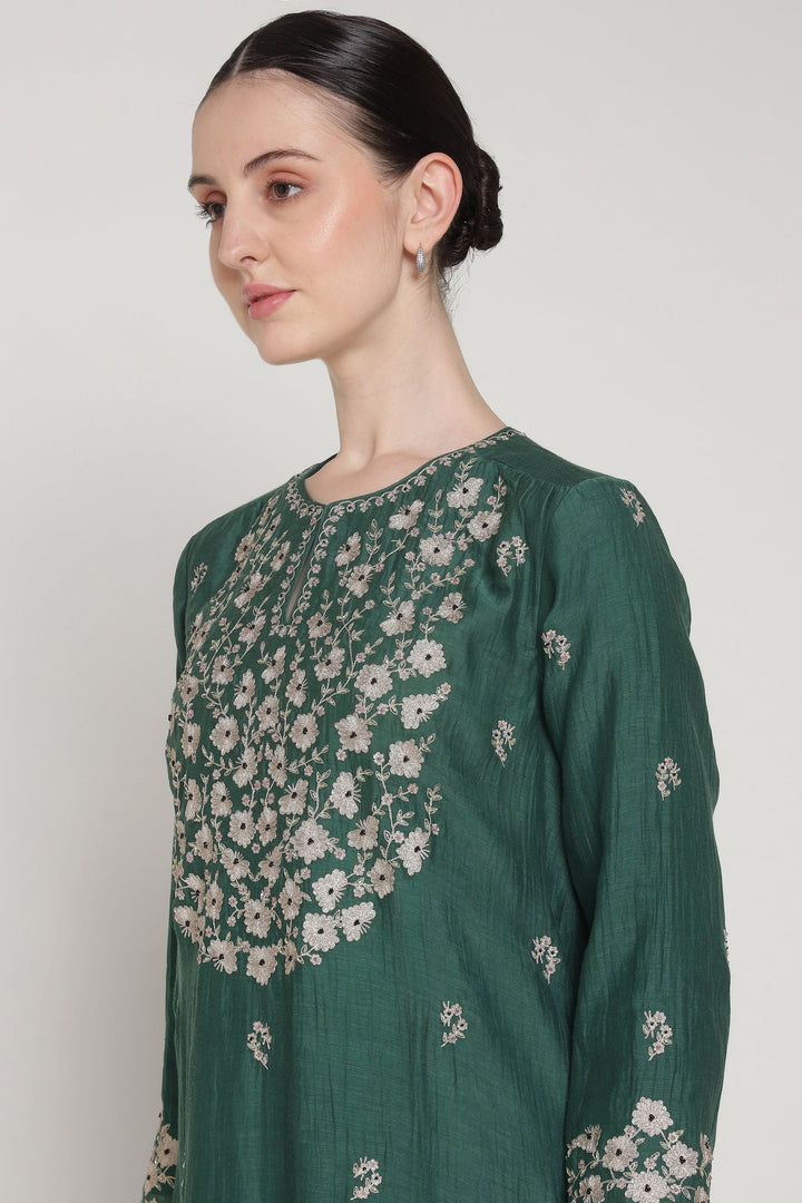 Green embroidered dress worn by a model against a plain background
