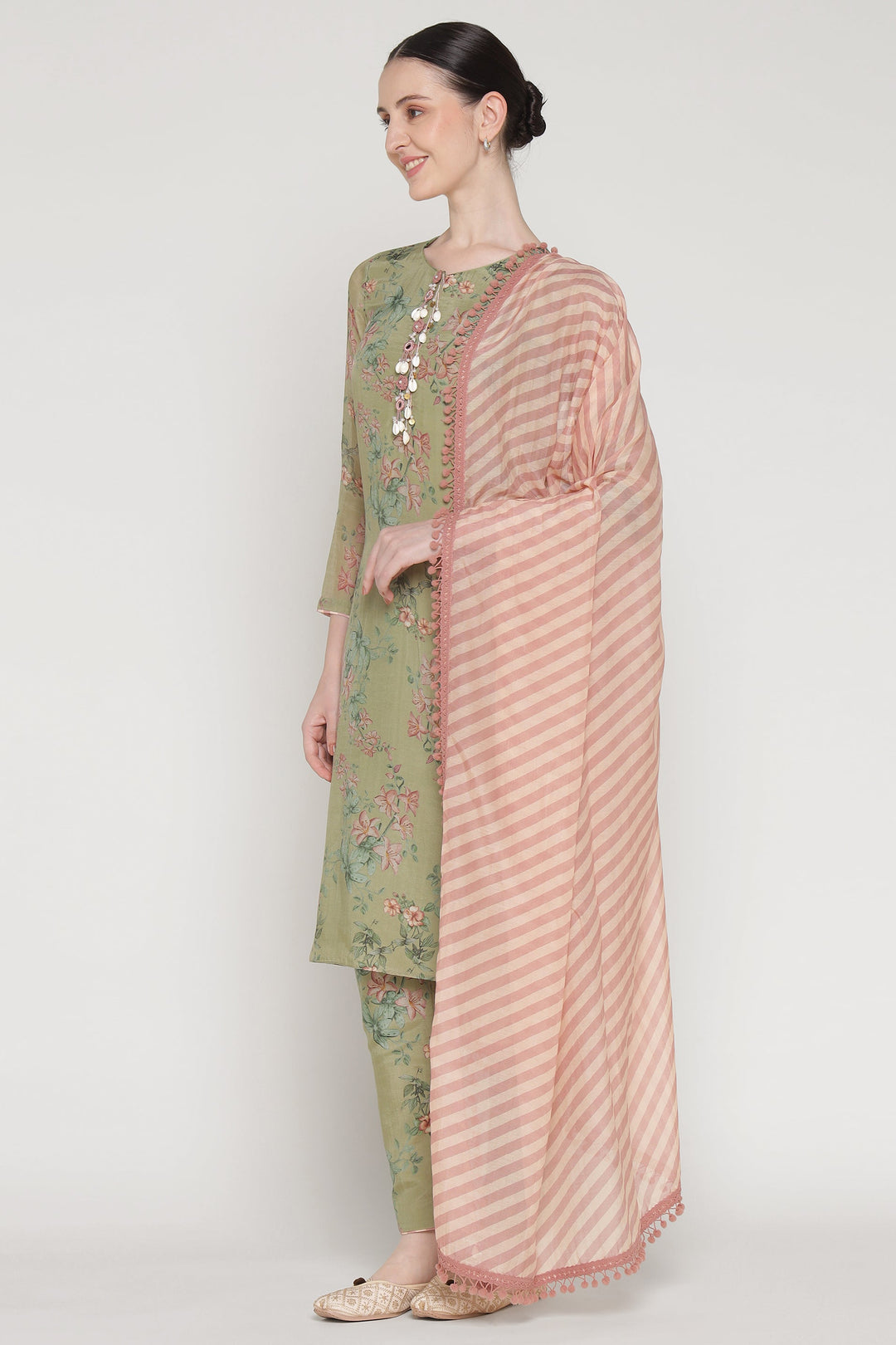 Woman wearing a green floral outfit with a pink dupatta on a white background