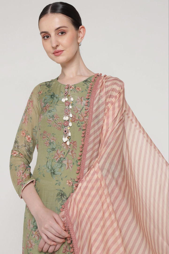 Woman wearing a green embroidered outfit with a pink dupatta on a white background