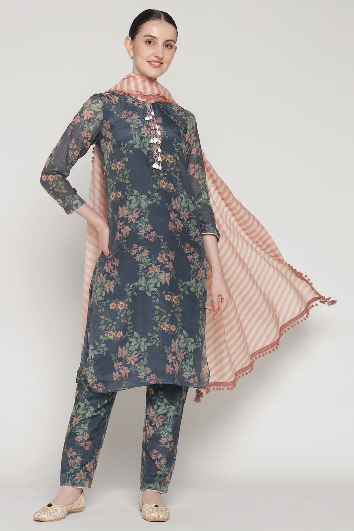 Woman wearing a floral kurta with matching pants and a pink dupatta on a white background