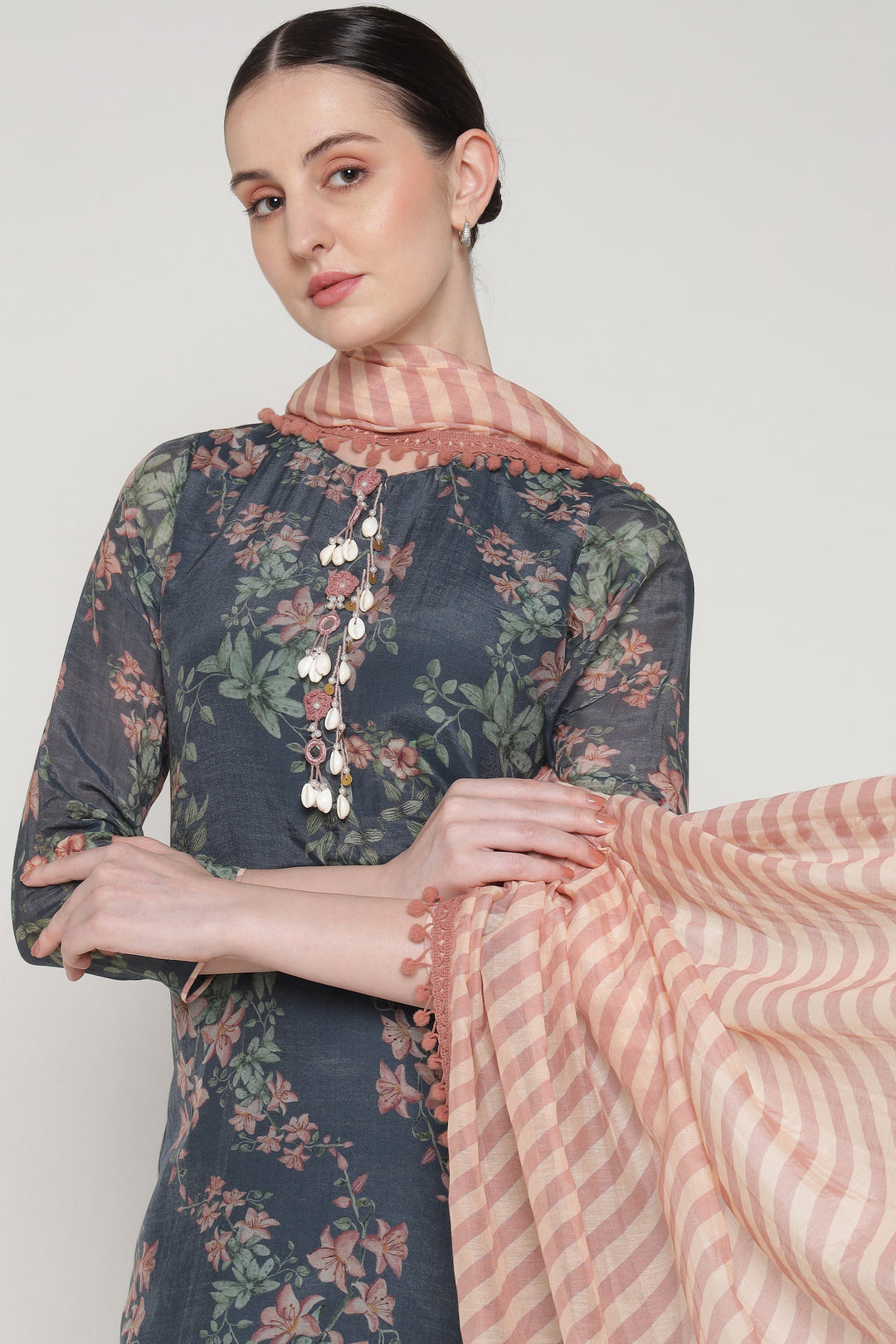 Woman wearing a floral dress with a matching shawl on a plain background