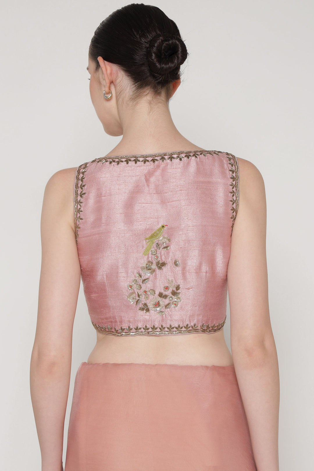 Pink embroidered blouse worn by a model on a plain background