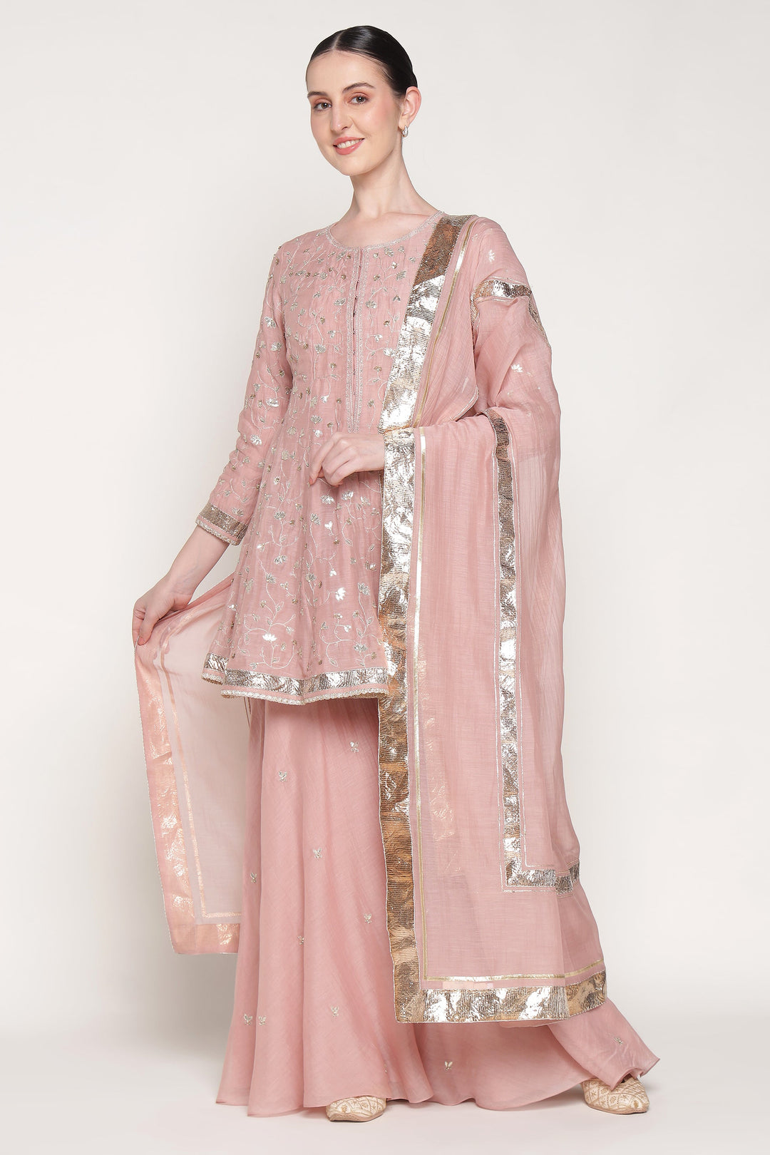 Woman wearing a pink traditional outfit with silver accents on a white background