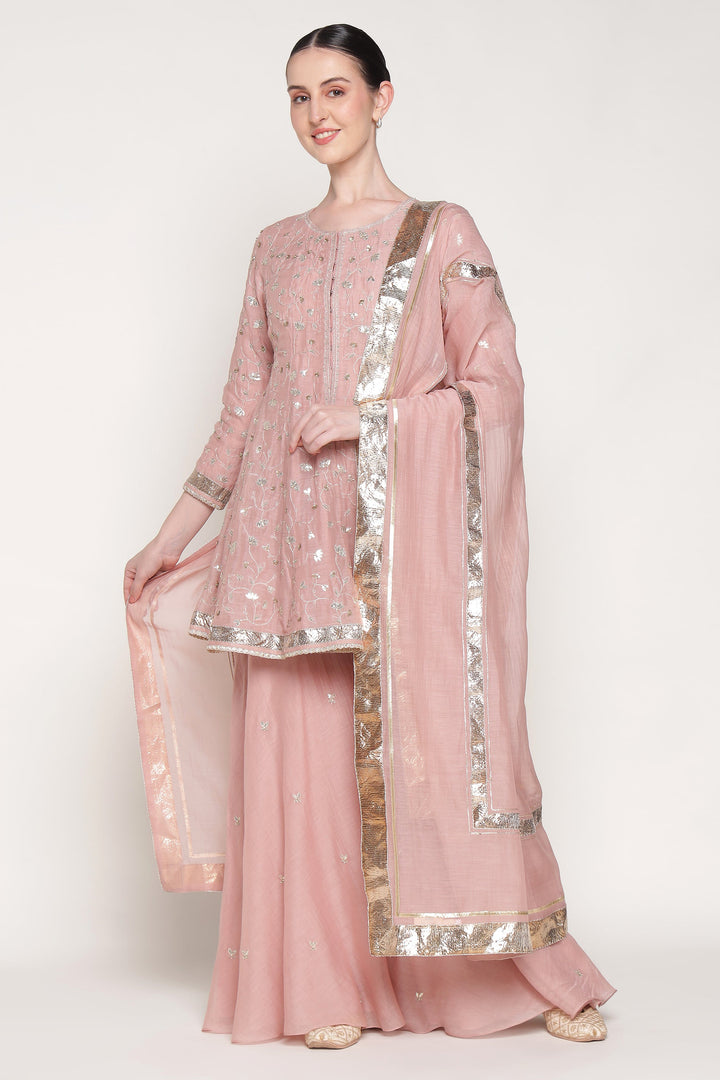 Woman wearing a pink traditional outfit with silver accents on a white background