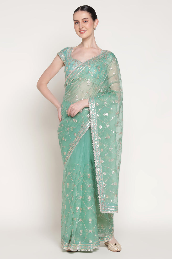 Woman wearing a light green saree with a white background