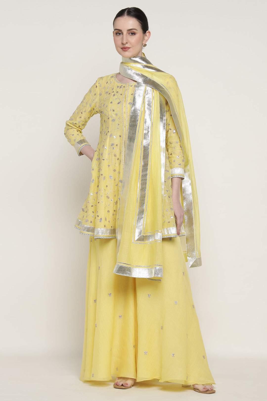 Woman wearing a yellow traditional outfit with silver accents on a white background